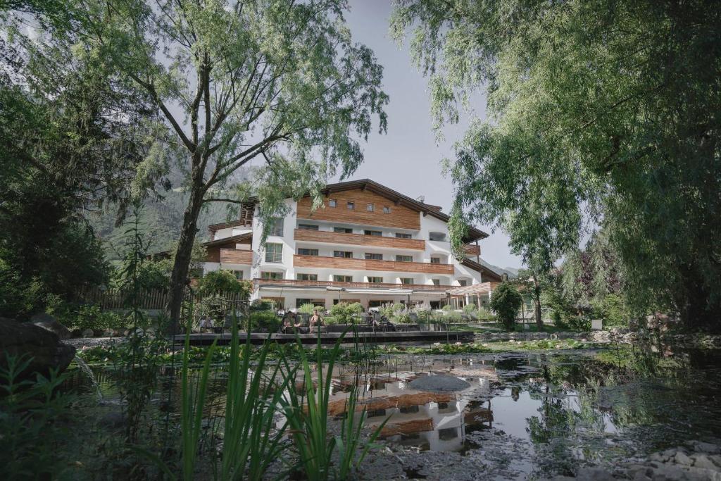 纳图尔诺Vegan Hotel La Vimea的 ⁇ 染一个拥有池塘和树木的酒店