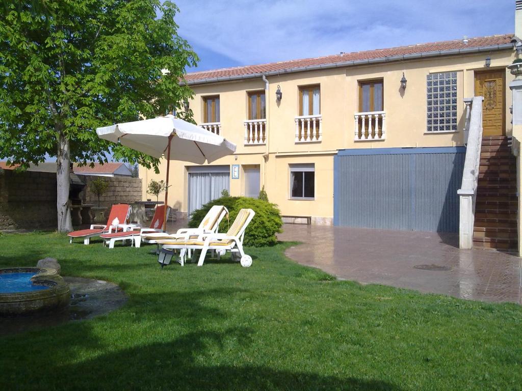 巴尔铁拉Casa Rural Sancho el Fuerte的一个带椅子和遮阳伞的庭院和一座建筑