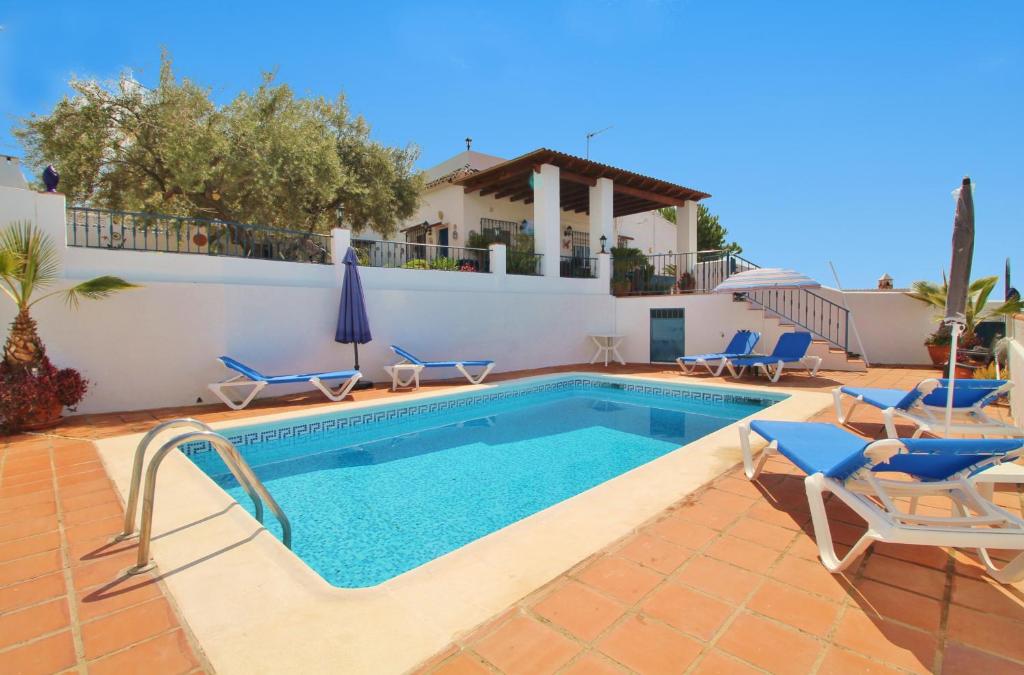 内尔哈Villa Cornocalejo SpainSunRentals 1003的一个带椅子的游泳池以及一座房子