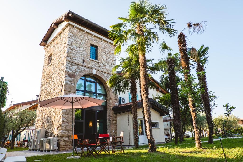 代森扎诺-德尔加达Villa Colli Storici的一座棕榈树建筑,一张桌子和一把伞