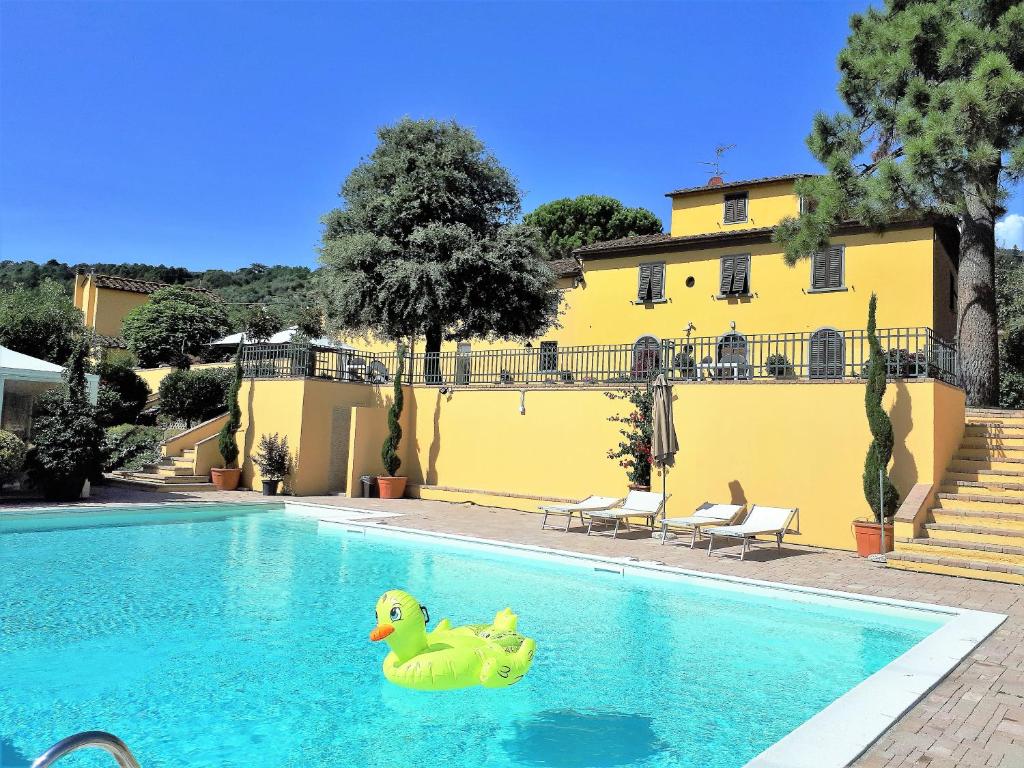塞拉瓦莱皮斯托耶塞Agriturismo Villa Bracali的两只橡皮杜基德在一座黄色建筑旁边的游泳池里