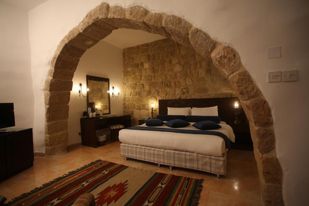 瓦迪穆萨老村度假酒店的一间卧室设有一张带石墙的大床
