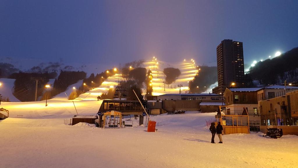 苏佩贝斯Studio-cabine au pied des pistes à Super Besse的一群人晚上站在雪中