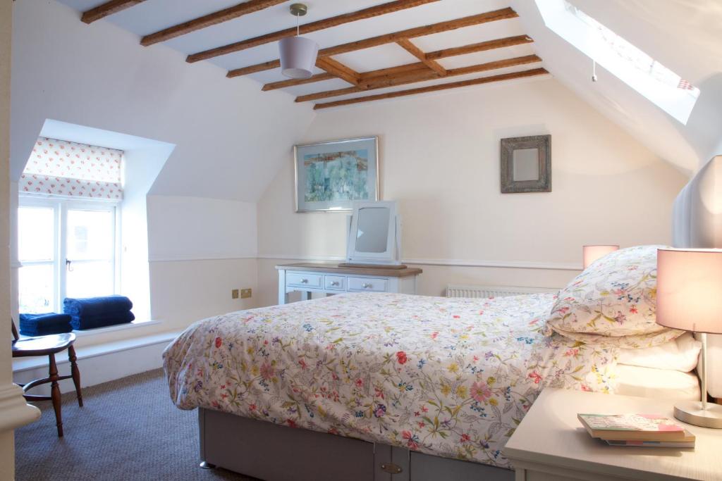 切达Strawberry Cottage的一间卧室配有一张床、一张书桌和一个窗户。