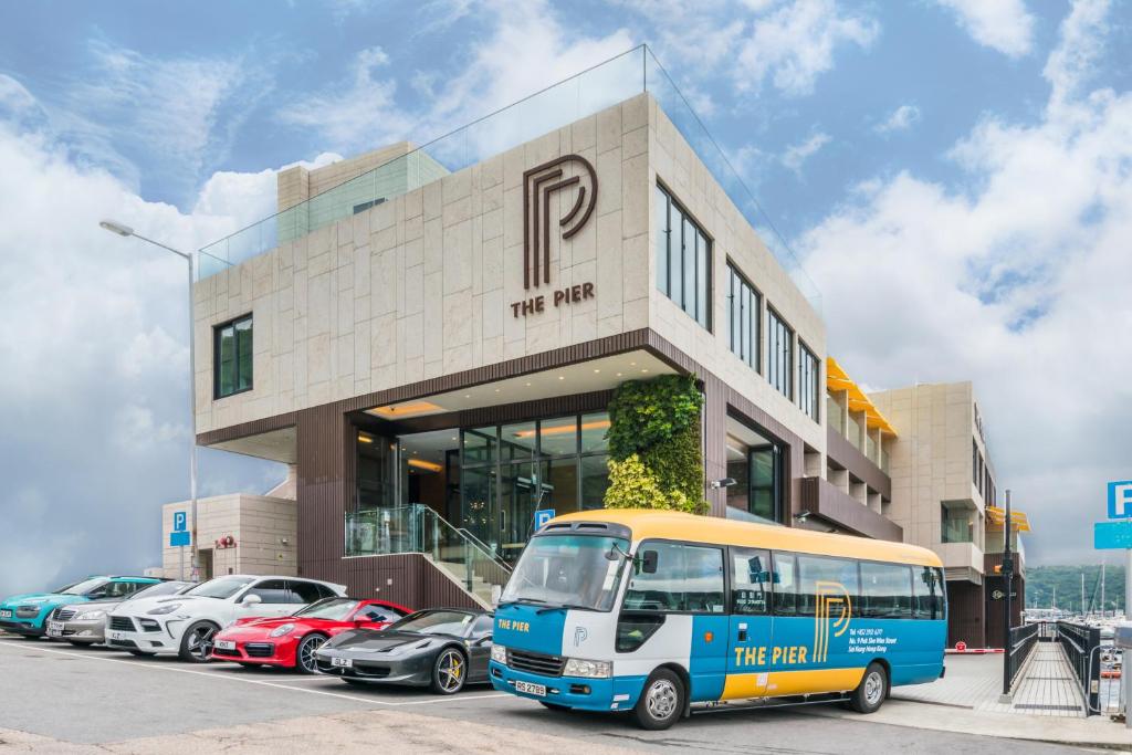 香港The Pier Hotel的停在有停车车的大楼前的公共汽车