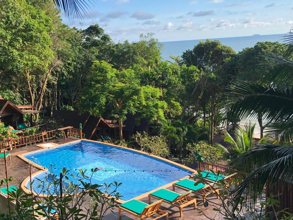 俊穆岛Koh Jum Ocean Beach Resort的一个带椅子的游泳池,背景是大海