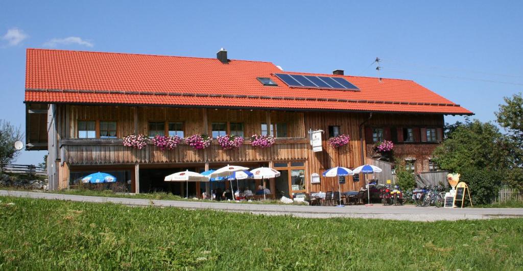 Maria Rain阿尔穆凯菲斯纳肯霍尔旅馆的一座带太阳能屋顶的建筑,配有桌子和遮阳伞