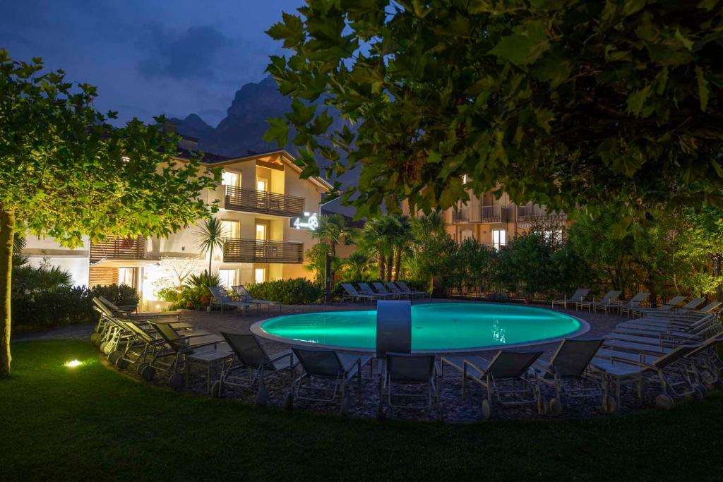 加尔达湖滨4丽莫尼公寓度假酒店的庭院里的一个游泳池,有椅子和一座建筑