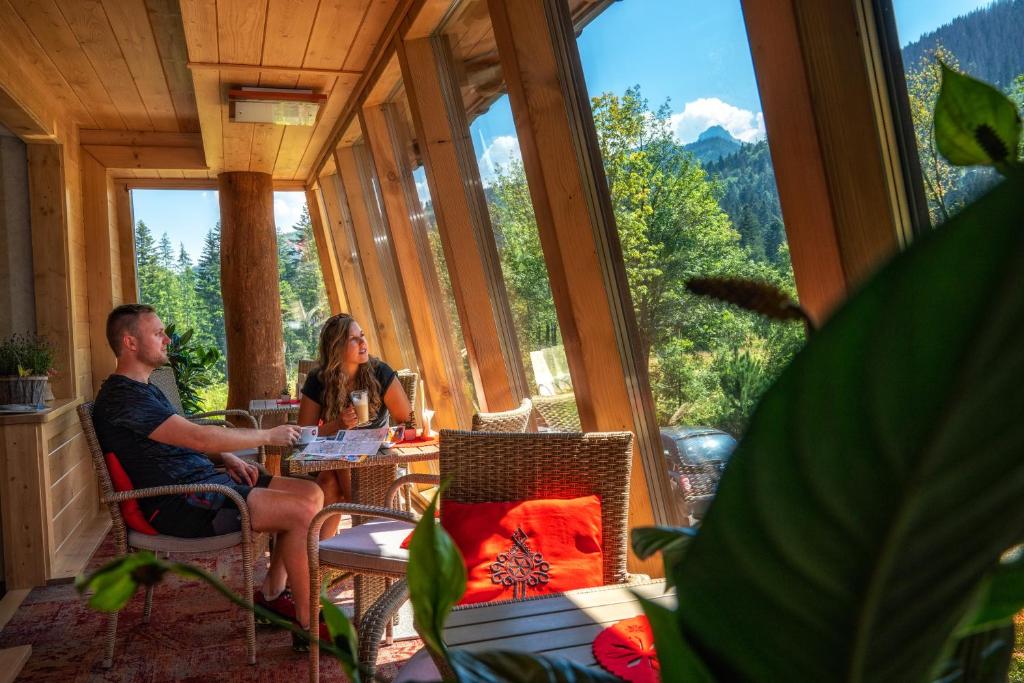 考斯赛力克Hotel Eco Tatry Holiday& Spa的坐在窗户房间里桌子上的男人和女人