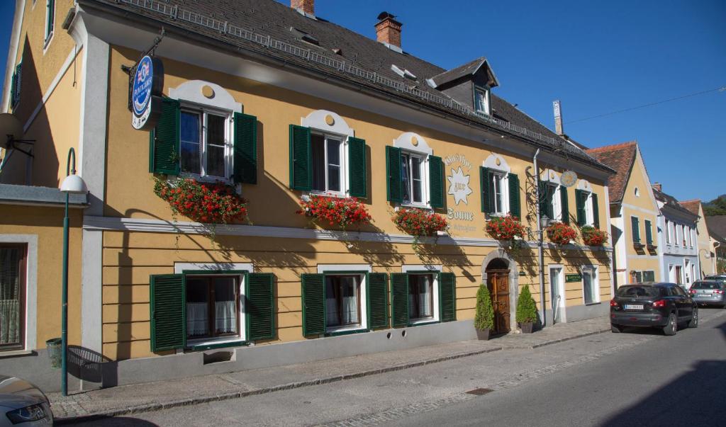 ÜbelbachGasthof zur Sonne的街道上一座带绿色百叶窗和鲜花的建筑