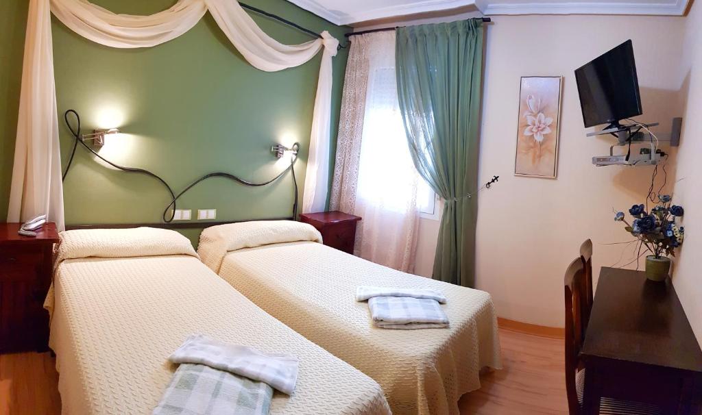 巴利亚多利德Hostal De La Torre Hostal Economico的一间卧室配有两张带毛巾的床