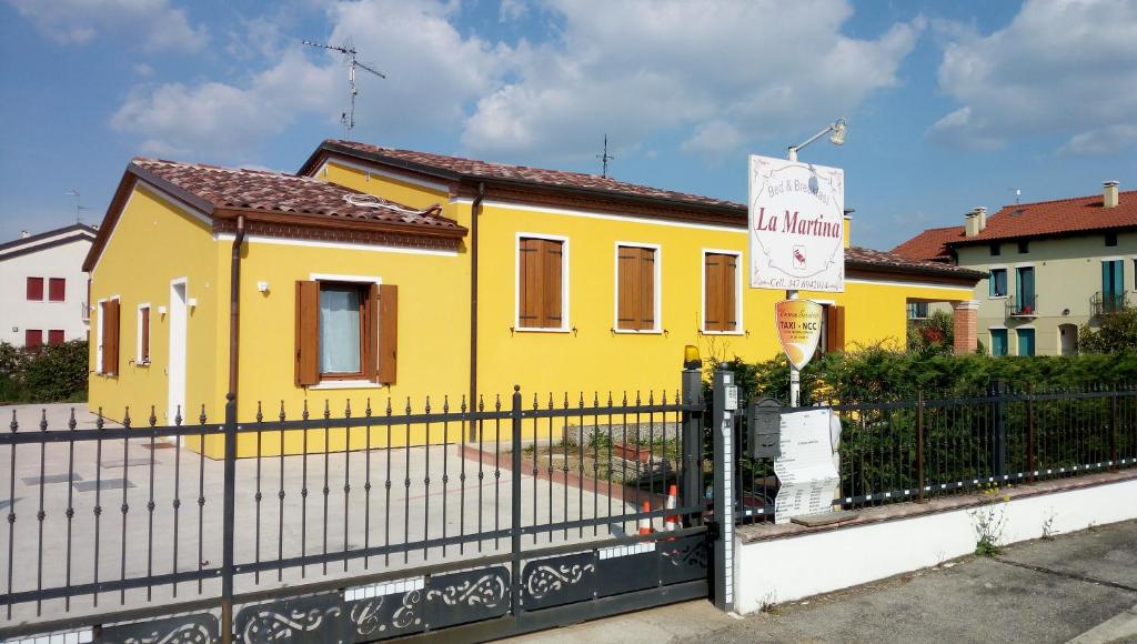 AgugliaroB&B Martina的前面有栅栏的黄色房子