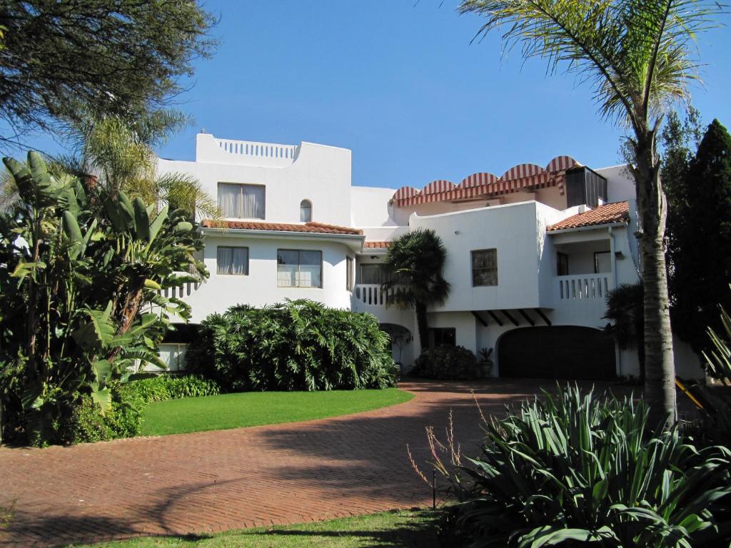比勒陀利亚科伦维德精品旅馆的棕榈树和车道的白色房子