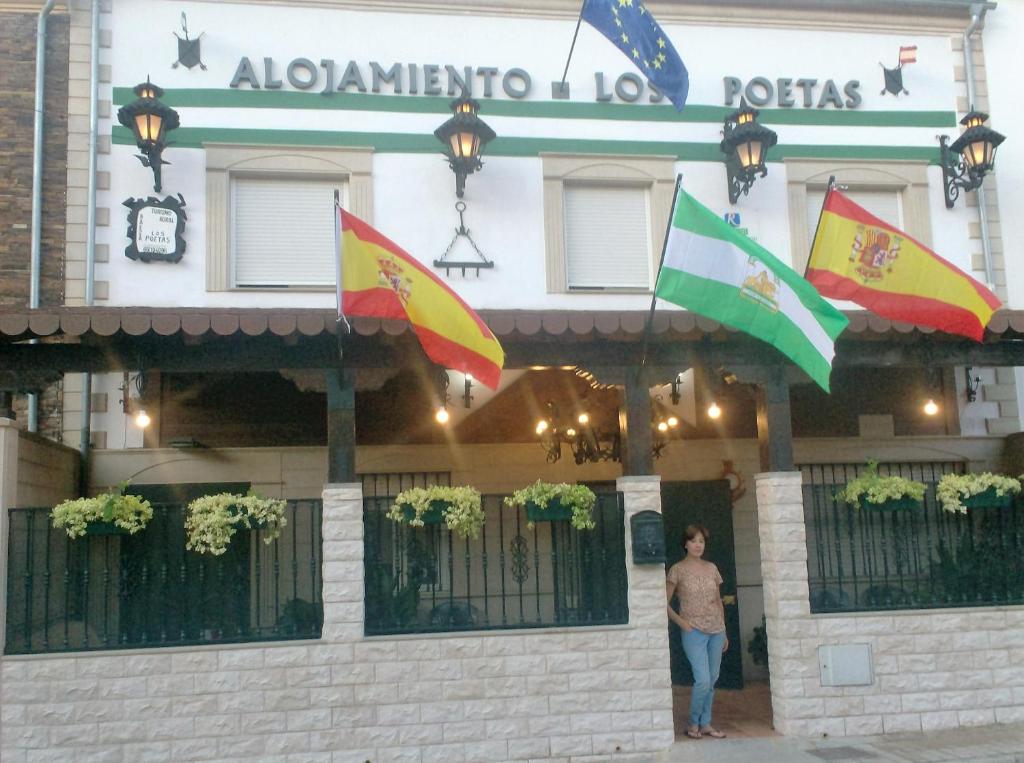 巴埃萨Alojamiento Los Poetas的站在有旗帜的建筑前的人