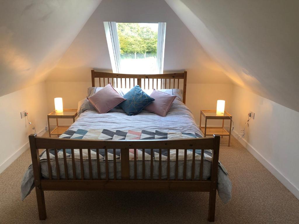 BlackfordThe Grey Cottage的卧室配有带枕头的床铺和窗户。