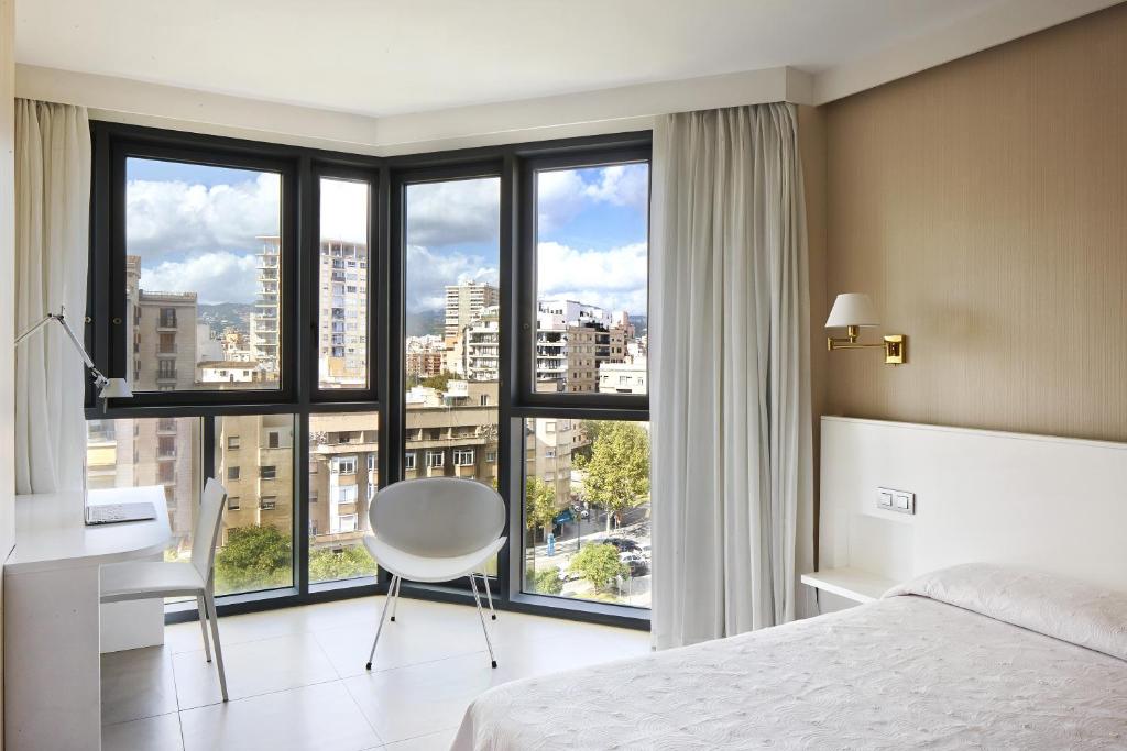 马略卡岛帕尔马守护神酒店的卧室配有一张床、一张书桌和窗户。