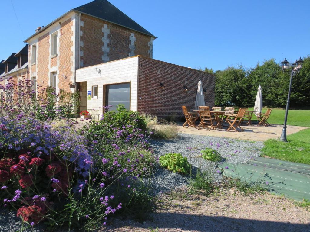 Sausseuzemare-en-Caux柳树池塘住宿加早餐旅馆的一座花园,在一座建筑前种有鲜花
