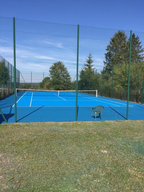GrandvillersHotel L'Ecrin 88 Vosges的蓝色的网球场,上面有长凳
