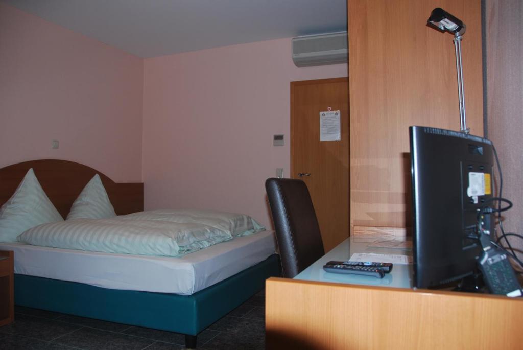 达姆施塔特加尔达酒店&餐厅的客房设有一张床、一张书桌和电视