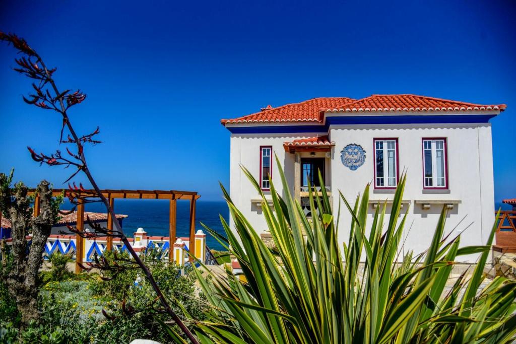 辛特拉Chalet O Amorzinho Sintra Praia的一座白色的建筑,有红色的屋顶和海洋