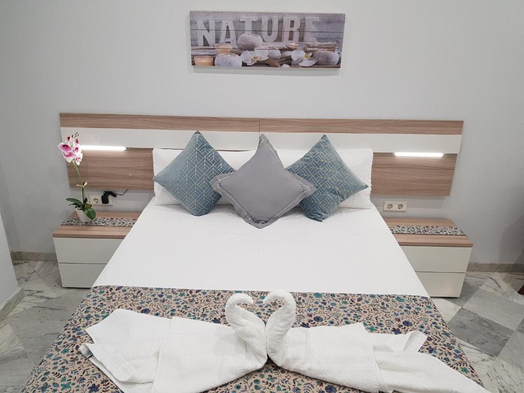科尔多瓦Apartamento Capuchinos Cordoba的卧室配有一张白色床和两只白色弓