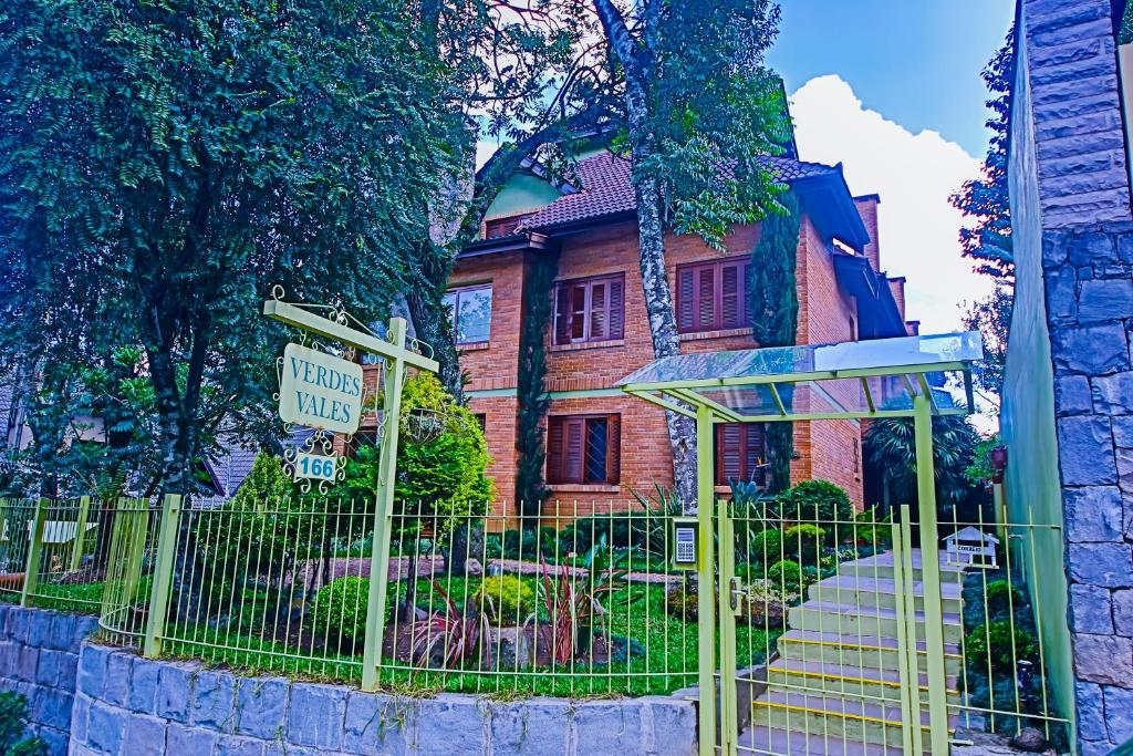 格拉玛多Suítes Belvedere - Apto Individual的前面有黄色围栏的房子