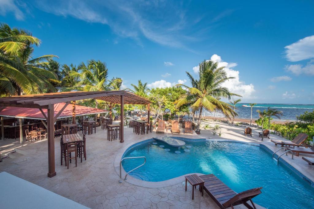 圣佩德罗Bella Vista Resort Belize的一个带桌椅的游泳池以及大海