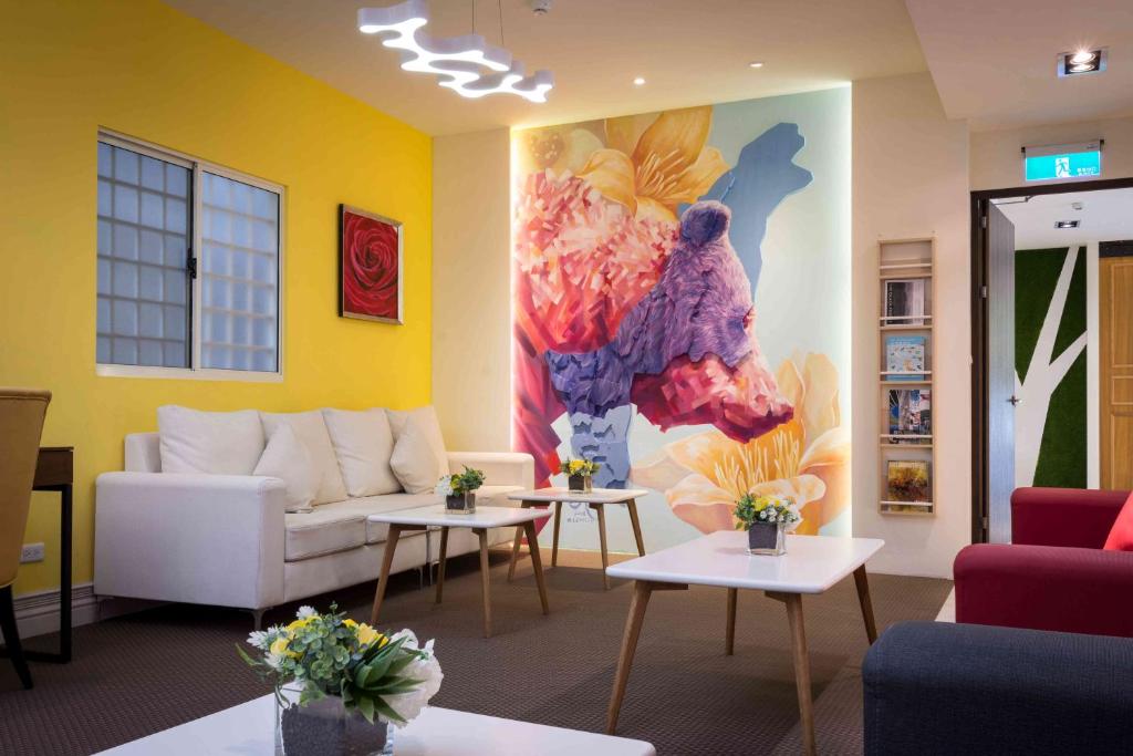 高雄日光花园商务饭店的客厅配有沙发、桌子和绘画作品