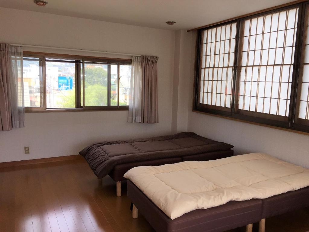 小田原市Guesthouse LARGO的带2扇窗户的客房内的2张床