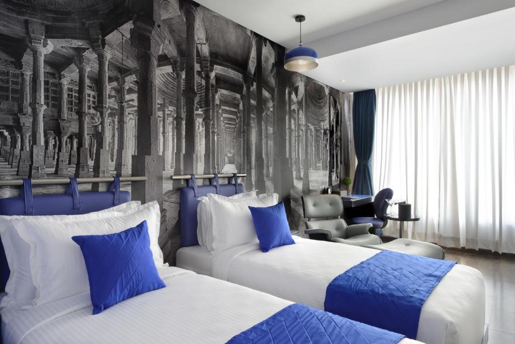 艾哈迈达巴德Regenta Central Antarim Ahmedabad的酒店客房,配有两张床和椅子