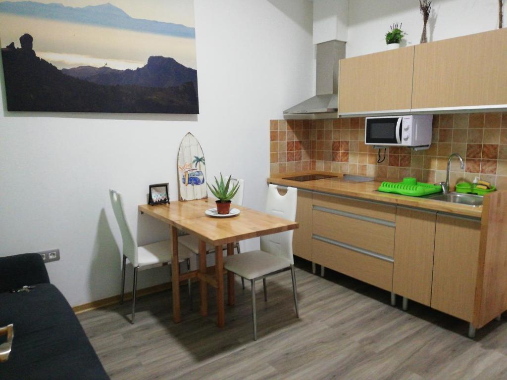 阿里纳加Apartamento la piedra viva 3 arinaga的小厨房配有木桌和桌椅