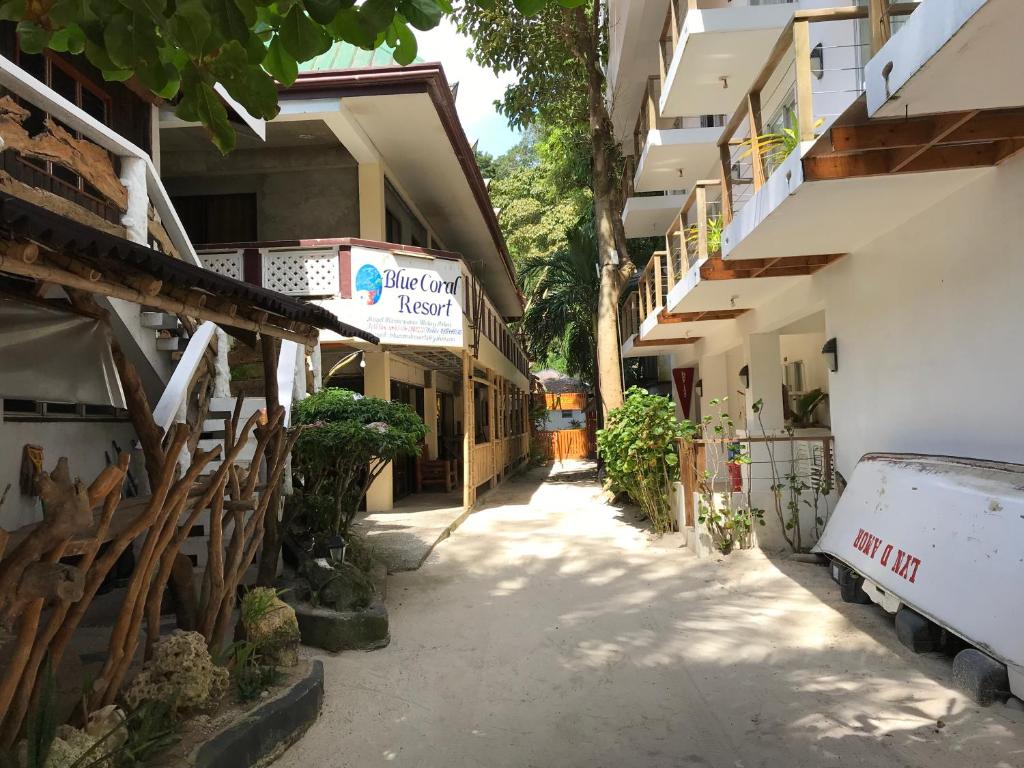 长滩岛蓝珊瑚长滩岛住宿加早餐旅馆的两栋建筑之间的小巷,前面有一辆面包车