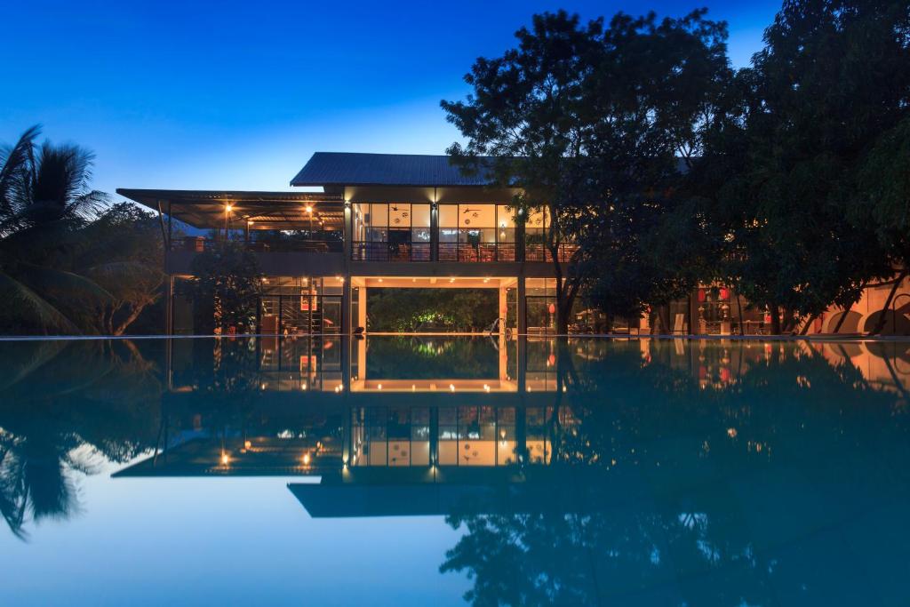 丹不拉Sigiriana Resort by Thilanka的夜晚在水中反射的房屋