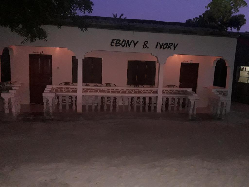 南威Ebony & Ivory Beach Bungalows的白色的建筑,晚上外面有椅子