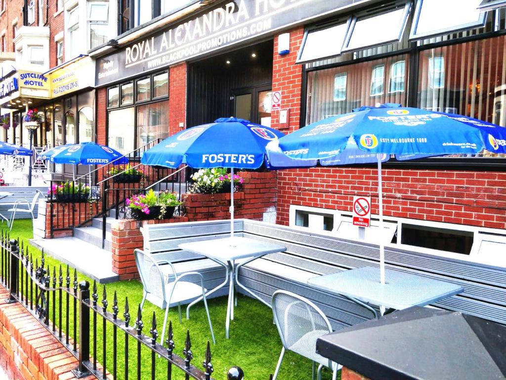 布莱克浦皇家亚历山德拉酒店的大楼前的餐厅,配有桌子和遮阳伞