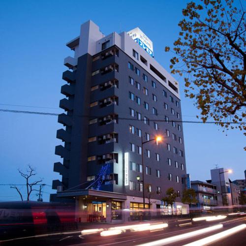 谏早市New Station Hotel Premiere的夜幕降临的城市街道上一座高楼