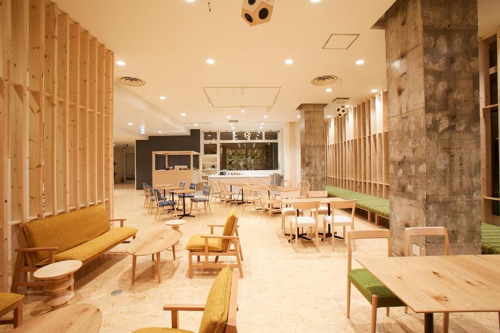 福岛YUMORI ONSEN HOSTEL的餐厅设有木桌、桌椅和长椅
