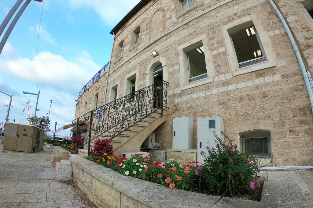 海法Haifa Hostel的砖砌的建筑,上面有楼梯和鲜花