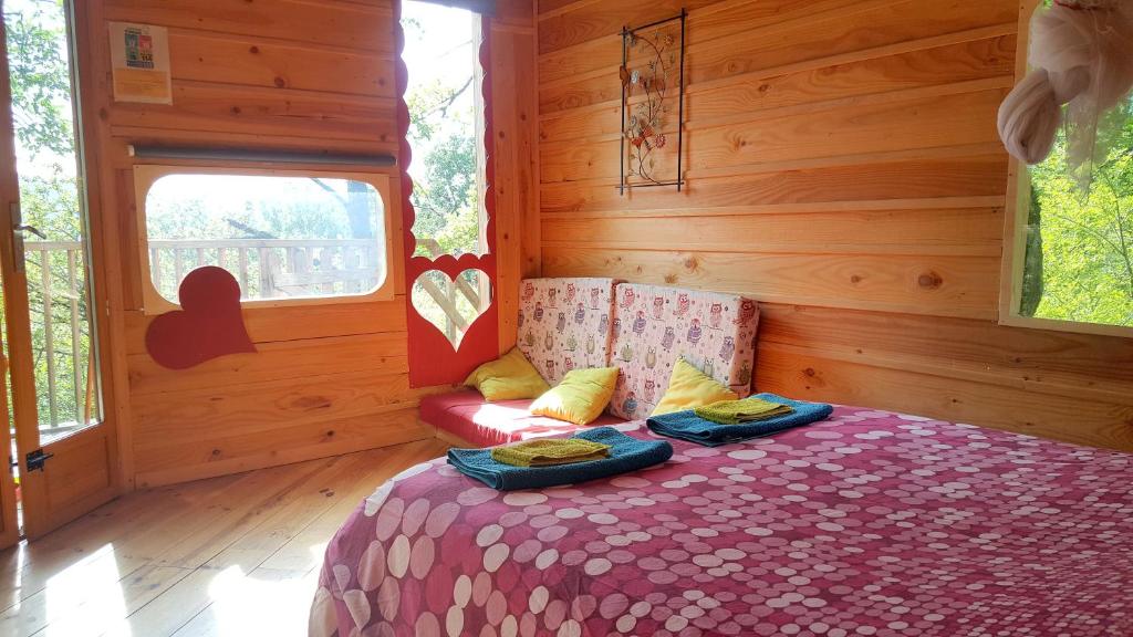 Saint-Victor-RouzaudCabanes Sainte Camelle的木制客房内的一间卧室,配有一张床
