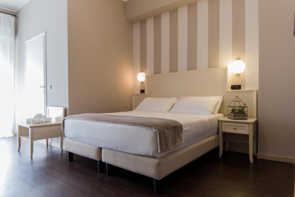 里米尼塞雷娜公园酒店的一间卧室设有一张大床和条纹墙