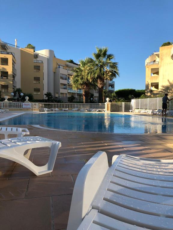 滨海卡涅Front beach Luxury near Nice airport的城市中带白色长凳的游泳池