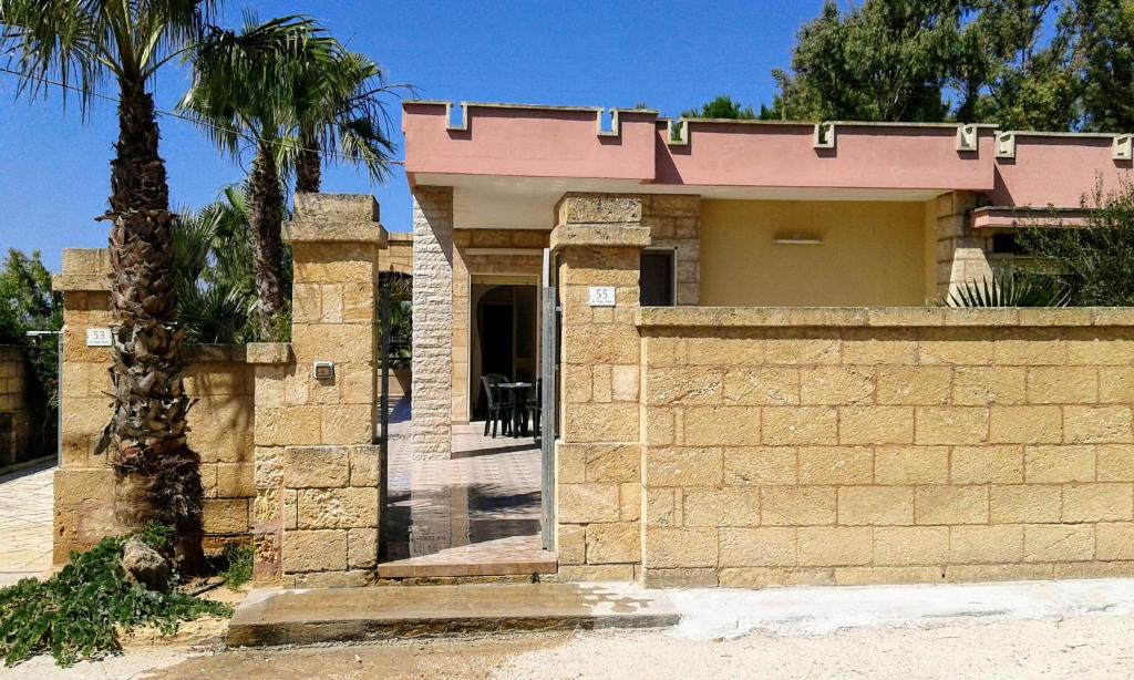 托雷圣乔万尼乌Casa vacanze Consiglia的一座砖墙和棕榈树的房子
