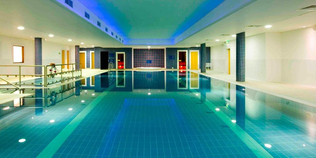 利默里克利姆瑞克玛尔德文酒店及休闲中心的大楼内一个蓝色瓷砖的大型游泳池
