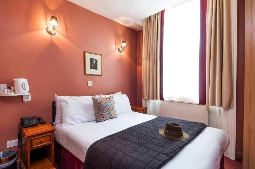伦敦Park Avenue Inn Craven London Hyde Park的酒店客房,配有带帽子的床