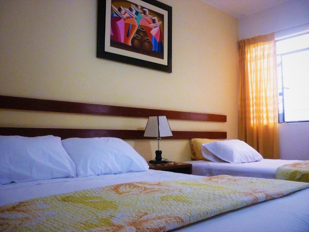 纳斯卡Anccalla Inn Guesthouse的酒店客房设有两张床,墙上挂着一张照片。