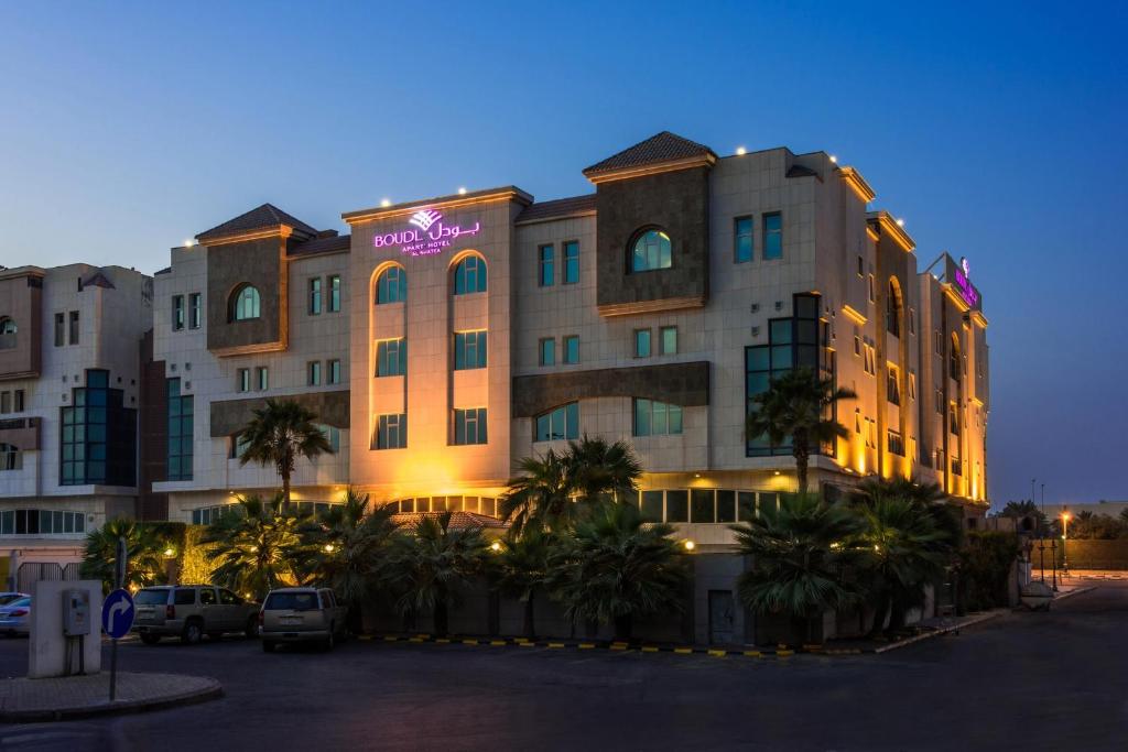 达曼博欧阿尔沙堤酒店的停车场内棕榈树的酒店大楼