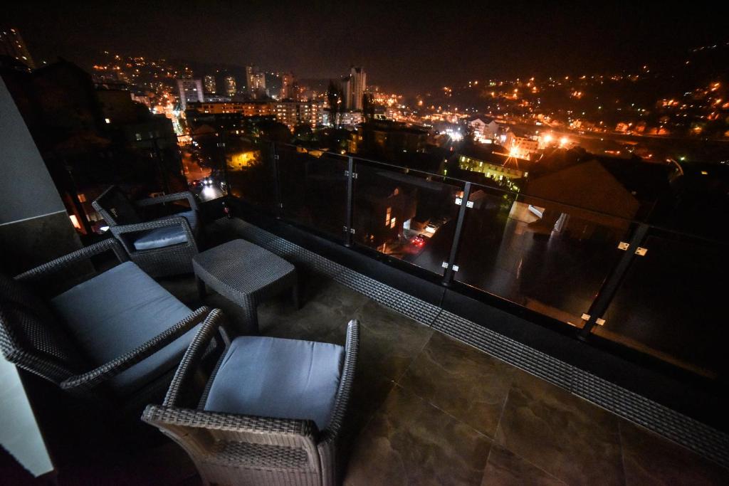 乌日策ANA LUX的阳台配有椅子,晚上可欣赏到城市美景