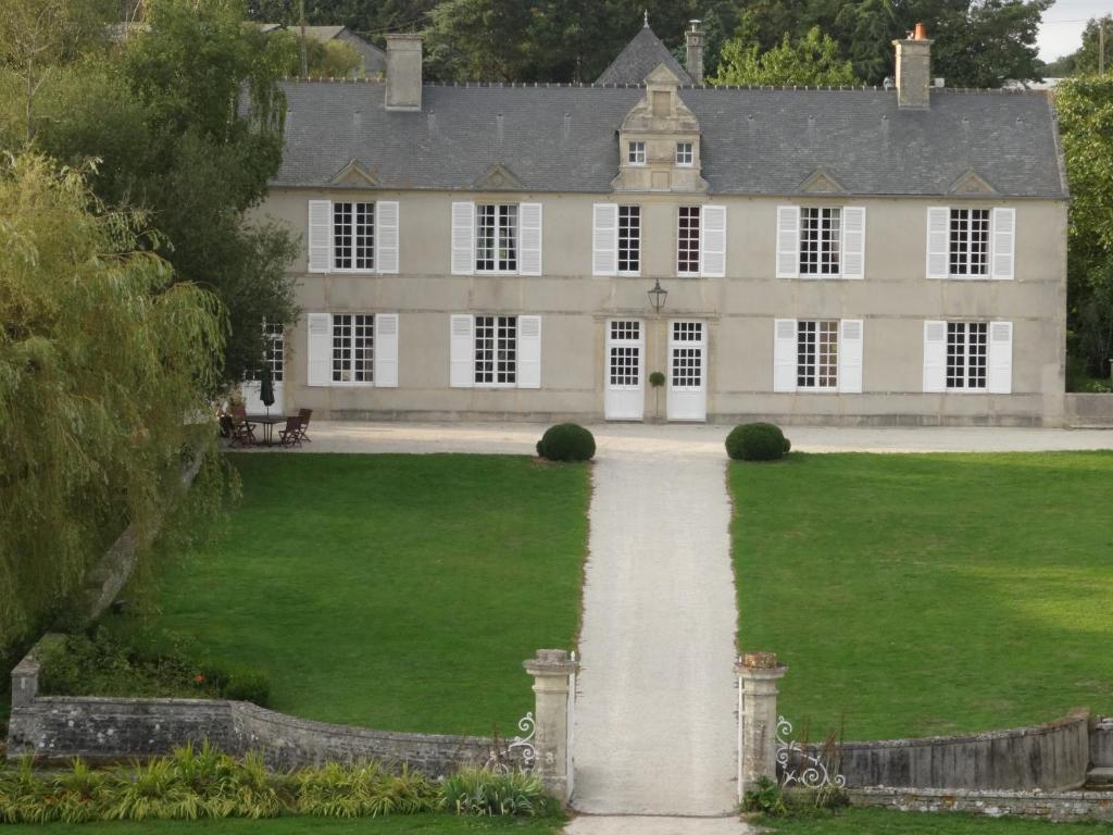 CrouayManoir de Conjon的一座带绿色草坪和小径的大房子