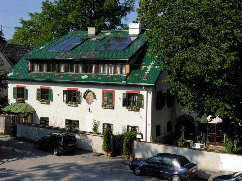 萨尔茨堡豪斯瓦顿伯格酒店的一座有绿色屋顶的房子,前面有汽车停放