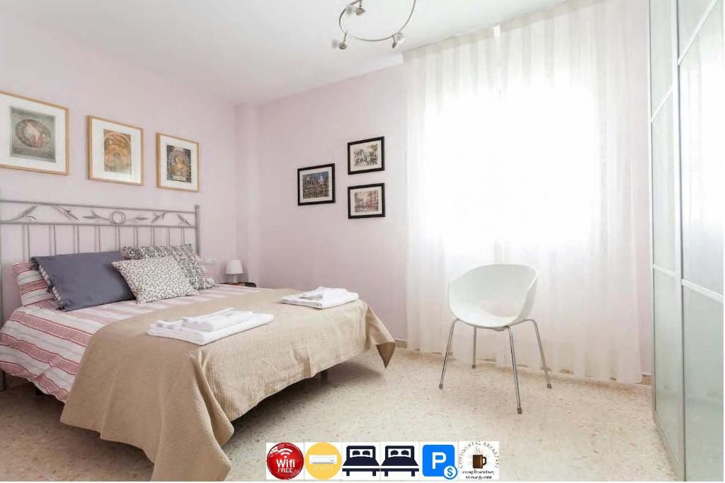 塞维利亚Apartamento Jardin de Santa Paula的卧室配有床、椅子和窗户。
